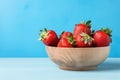 Fresh juicy strawberries in wood bowl on light blue table