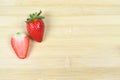 Fresh Juicy Strawberry and a slice cut isolated on wood background