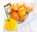 Fresh juicy summer fruits, oranges, mango, kiwi in a vintage basket and refreshment drinks on a wooden table on a white background Royalty Free Stock Photo