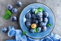 Fresh juicy sweet plums on plate with leaves