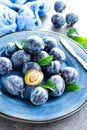 Fresh juicy sweet plums on plate with leaves Royalty Free Stock Photo