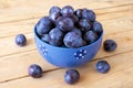 Fresh juicy sweet plums on plate with leaves on wooden background Royalty Free Stock Photo