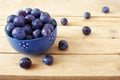 Fresh juicy sweet plums on plate with leaves on wooden background Royalty Free Stock Photo