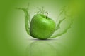 A fresh, juicy and tasty green apple causing water splash in all directions. Green background.