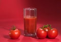 Fresh juicy tomatoes and juice on a red background Royalty Free Stock Photo