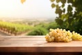 Fresh juicy white vine grapes on rustic wooden table with blurred vineyard background