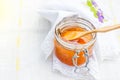 Fresh , just now collected honey in the opened glass jar on a white background, teaspoon with honey above it