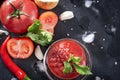 Fresh ketchup with a sprig of  parsley, herbs, tomato slices, red chili pepper, garlic, ice cubes, on a black background, sauce Royalty Free Stock Photo