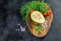 Fresh keto diet avocado stuffed with tuna and sauce, tomatoes cherry and greens on the kitchen wooden cutting board. Top view,