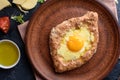 Fresh khachapuri with wholegrain flour, cottage cheese, egg, sulugini cheese, vegetables, butter, greens, plate, fork knife