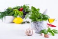 Fresh kitchen herbs and spices, oil with a white ceramic mortar.