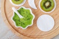 Fresh kiwi fruit puree in a small white bowl and cotton pad. Homemade face or eye mask, natural beauty treatment and spa recipe.