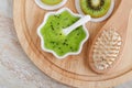 Fresh kiwi fruit puree in a small white bowl and wooden hair brush. Homemade hair or face mask, natural beauty treatment and spa