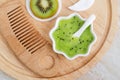 Fresh kiwi fruit puree in a small white bowl and wooden hair brush. Homemade hair or face mask, natural beauty treatment and spa
