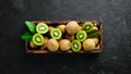 Fresh kiwi and green leaves in a wooden box on the old background. Fruits. Top view. Royalty Free Stock Photo