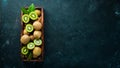 Fresh kiwi and green leaves in a wooden box on the old background. Fruits. Top view. Royalty Free Stock Photo