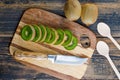 Fresh kiwi with knife, spoons flat lay on wooden and cutting board background Royalty Free Stock Photo