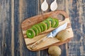 Fresh kiwi with knife, spoons on wooden and cutting board background, top view Royalty Free Stock Photo