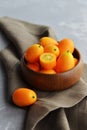 Fresh kumquat fruits in wooden bowl on linen background. Healthy vegan food. Royalty Free Stock Photo