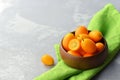 Fresh kumquats in wooden bowl on flax napkin on grey background. Healthy vegan food. Copy space Royalty Free Stock Photo