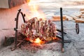 Fresh lamb meat on an open fire on a skewer for roasting-jack. daylight, wooden blocks are visible in the background