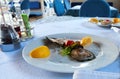 Fresh large oysters, beautifully garnished with lemon slices, on a spotless white plate on a crisp white tablecloth