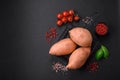 Fresh large pink sweet potato tubers with tomatoes and spices on a dark background Royalty Free Stock Photo