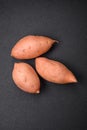 Fresh large pink sweet potato tubers with tomatoes and spices on a dark background Royalty Free Stock Photo