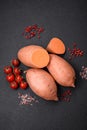 Fresh large pink sweet potato tubers with tomatoes and spices on a dark background Royalty Free Stock Photo