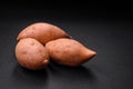 Fresh large pink sweet potato tubers with tomatoes and spices on a dark background Royalty Free Stock Photo