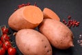 Fresh large pink sweet potato tubers with tomatoes and spices on a dark background Royalty Free Stock Photo