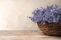 Fresh lavender flowers in basket on wooden table against beige background Royalty Free Stock Photo