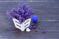 Fresh lavender in white basket, purple candle and heart on grey wooden background