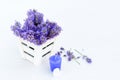 Fresh lavender in white basket, purple candle and heart on white wooden background.