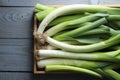 Fresh leeks in crate on grey wooden table, top view Royalty Free Stock Photo