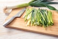 Fresh leeks cut into thin strips and a kitchen knife on a wooden board, prepared vegetables for cooking a healthy vegetarian dish