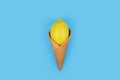 Fresh lemon in ice cream cone on light blue background. Royalty Free Stock Photo