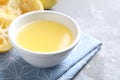 Fresh lemon juice in bowl and fruit on grey table, closeup Royalty Free Stock Photo