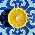 A fresh lemon slice is placed on a decorative ceramic tile with a traditional blue and Royalty Free Stock Photo