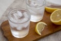 Fresh Lemon Sparkling Water with Ice on a rustic wooden board, side view. Close-up