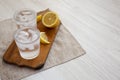 Fresh Lemon Sparkling Water with Ice on a rustic wooden board, side view. Copy space