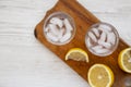 Fresh Lemon Sparkling Water with Ice on a rustic wooden board on a white wooden background, top view. Copy space