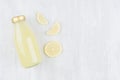 Fresh lemon yellow juice in glass bottle with gold cap, sliced fruit on white wood board, top view, copy space, mock up for design Royalty Free Stock Photo