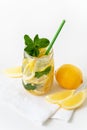 Fresh lemonade in a glass jar with green paper straw, lemon slices and mint on the white napkin. Royalty Free Stock Photo