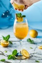 Fresh lemonade with mint, lemon and ice in wineglass on light blue background. Man hand squeezes lime juice from lemonade cocktail Royalty Free Stock Photo