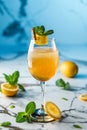 Fresh lemonade with mint, orange and ice in wineglass on light blue background. Summer cold drink and cocktail Royalty Free Stock Photo