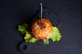 Fresh lettuce leaves on sides, black background, top view big burger with fork inside