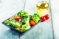 Fresh lettuce salad with cherry tomatoes radish and carafe with olive oil on wooden table. Royalty Free Stock Photo