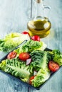 Fresh lettuce salad with cherry tomatoes radish and carafe with olive oil on wooden table. Several ingredients of Mediterranean cu Royalty Free Stock Photo