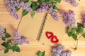 Fresh lilac flowers,  empty notepad and two red hearts on wooden background. Royalty Free Stock Photo